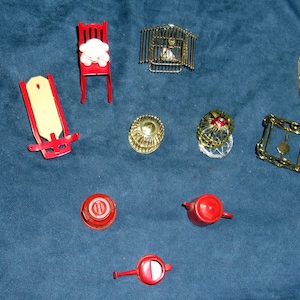 May include: A collection of miniature red and gold metal ornaments, including a rocking chair, a sled, a bench, a cage, a watering can, a teapot, and a few other decorative pieces.