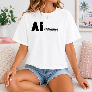 Peut inclure: Un t-shirt blanc à manches courtes avec le texte noir AI ntelligence imprimé sur le devant. Le t-shirt présente une encolure ronde et une coupe décontractée, associé à un short en jean bleu clair avec un ourlet effiloché sur le bas.