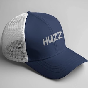 Op de afbeelding: Een marineblauwe truckerpet met een witte mesh achterkant en een gebogen klep. Het woord "HUZZ" is in witte, gestileerde letters op de voorkant gedrukt. De pet is ontworpen om te worden gedragen met de klep naar voren.