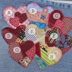 May include: A collection of handmade fabric heart patches in various patterns and colors, including floral, polka dot, and plaid. Each heart is stitched onto a denim background, creating a patchwork design. Some hearts have buttons or star embellishments.