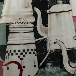 May include: Fabric featuring a collage of vintage-style coffee pots in shades of white, cream, and red against a black background. The design includes script writing and a green teapot.
