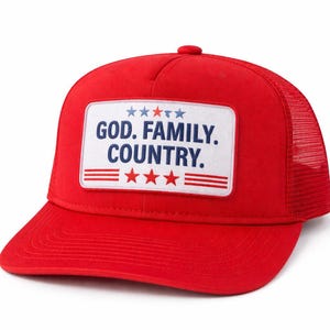 May include: A red trucker hat with a white patch featuring the text "GOD. FAMILY. COUNTRY." The patch includes blue stars and red stripes. The hat has a mesh back and a curved brim.