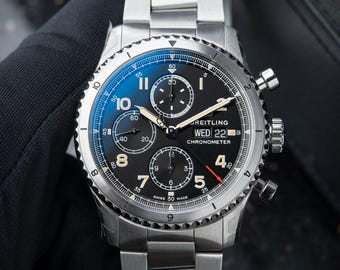 Reloj Breitling Aviator 8 Cronógrafo Day Date Vintage con esfera negra y brazalete de acero, ideal para hombre o como regalo.