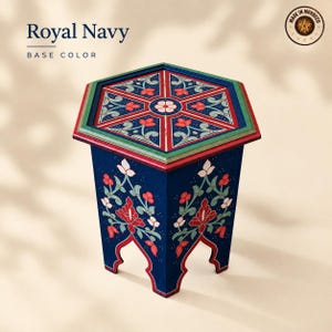 May include: A hexagonal side table with a royal navy base color, featuring intricate hand-painted floral patterns in red, white, and green. The top surface displays a geometric design with a central flower motif, and the sides have arched cutouts.