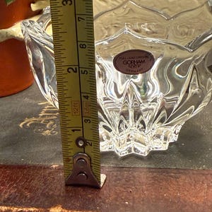May include: Clear crystal bowl with a scalloped rim and a starburst base. The bowl is approximately 2 inches (5 cm) tall. A label reads "GORHAM GERMANY".