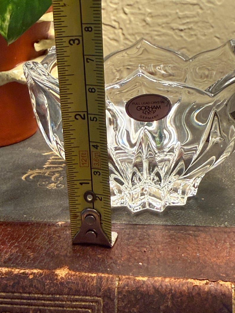 May include: Clear crystal bowl with a scalloped rim and a starburst base. The bowl is approximately 2 inches (5 cm) tall. A label reads "GORHAM GERMANY".