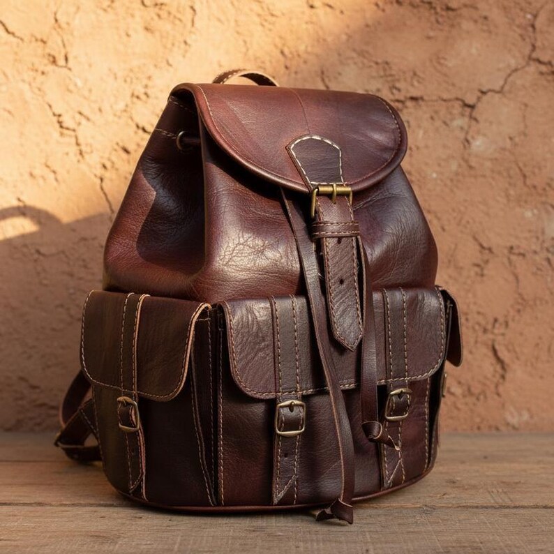Vintage dark brown leather backpack with buckle front pockets and detailed stitching, handmade rustic travel rucksack for work, college, hiking and everyday carry
