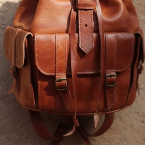 Handmade brown leather backpack with front buckle pockets and adjustable straps, vintage travel rucksack with detailed stitching, rustic leather bag for everyday carry and adventure