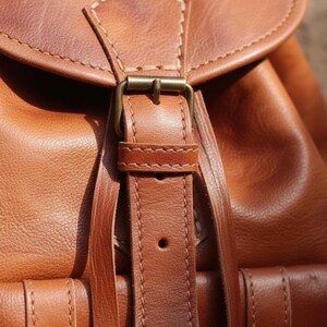 Close up of handmade brown leather backpack buckle and stitching, full grain leather craftsmanship with vintage brass hardware and rustic artisan details