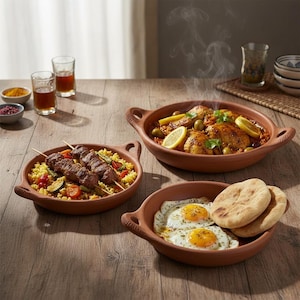 以下が含まれることがあります： 木製のテーブルに、食べ物が入ったテラコッタの皿が3つ並んでいます。1つの皿にはクスクスの上にケバブ、別の皿にはオリーブとレモンスライスを添えたチキン、3つ目には目玉焼きとピタパンが入っています。スパイスの小鉢と液体が入ったグラスも置かれています。