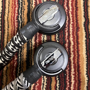 May include: Two black and silver audio cables with the text "FertaFive" on the circular connector. The cables have a black and white zig-zag pattern on the handles. The background is a brown, red, and black patterned rug.