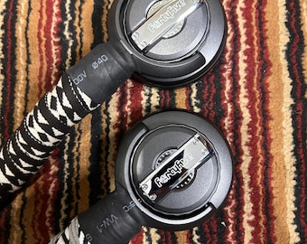 May include: Two black and silver audio cables with the text "FertaFive" on the circular connector. The cables have a black and white zig-zag pattern on the handles. The background is a brown, red, and black patterned rug.