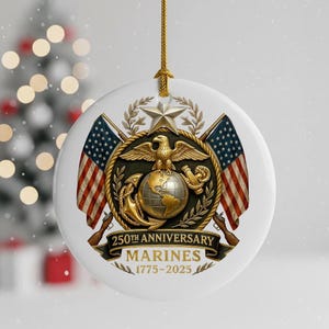May include: A white, round ornament with a gold string for hanging. The ornament features the emblem of the U.S. Marines, including an eagle, globe, and anchor, with two American flags. Text reads "250th Anniversary Marines 1775-2025."