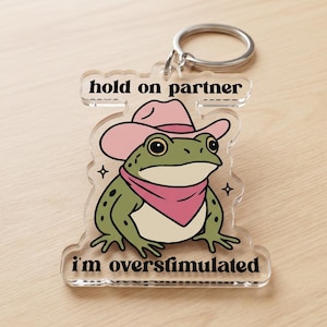 Overstimulated Frog Keychain - Funny Cowboy Frog Acrylic Keyring - Sarcastic Mental Health Gift - Hold On Partner Meme Charm
