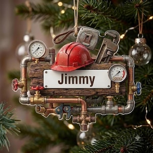 May include: A decorative ornament featuring a central white rectangular plaque with the name Jimmy printed in black. The plaque is framed by metallic pipes, valves, a red hard hat, a tape measure, a pipe wrench, and two round pressure gauges.