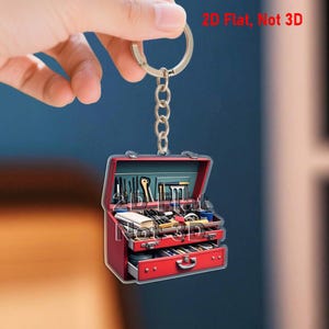 May include: A red toolbox keychain with a silver chain and ring. The keychain has two drawers and an open top, revealing miniature tools. The text "2D Flat, Not 3D" is visible in the image.