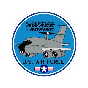 May include: A round sticker featuring a gray E-3 Sentry AWACS aircraft with the text "E-3 SENTRY AWACS BOEING" and "U.S. AIR FORCE" in a blue circle. The sticker includes the American flag and the numbers "2123" and "32123".