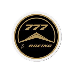 May include: A round sticker featuring the Boeing logo. The design includes the number "777" in gold, above a gold stylized wing shape, set against a black background. The word "BOEING" is in gold at the bottom.