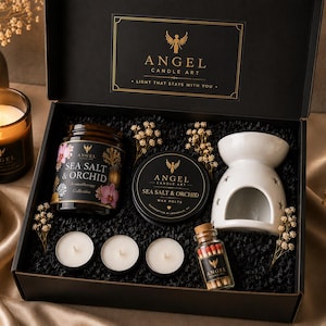 May include: A black gift box with a candle set, including a jar candle, wax melts, a ceramic oil diffuser, tea lights, and matches. The set features the "Angel Candle Art" brand, with floral and orchid accents.