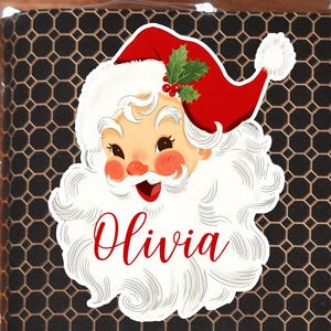 May include: A Santa Claus sticker with a red hat, white beard, and the name "Olivia" in red script. The sticker features a festive design with holly and berries, perfect for holiday decorations.