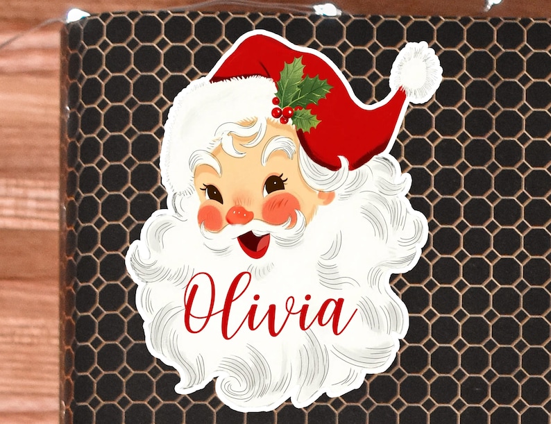 May include: A Santa Claus sticker with a red hat, white beard, and the name "Olivia" in red script. The sticker features a festive design with holly and berries, perfect for holiday decorations.
