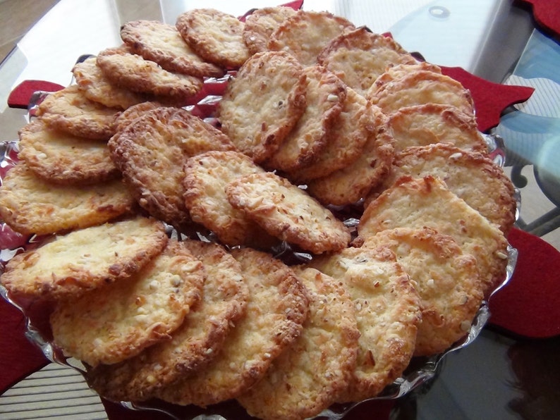 Puede incluir: Un plato de galletas doradas, crujientes y ligeramente dulces. Las galletas est&aacute;n dispuestas en c&iacute;rculo, con las galletas m&aacute;s grandes en el centro y las galletas m&aacute;s peque&ntilde;as alrededor de los bordes.