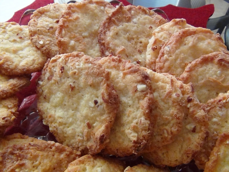 Puede incluir: Un plato de galletas doradas con una textura ligeramente crujiente. Las galletas est&aacute;n dispuestas en un patr&oacute;n circular y parecen estar hechas con una combinaci&oacute;n de mantequilla, az&uacute;car y harina.