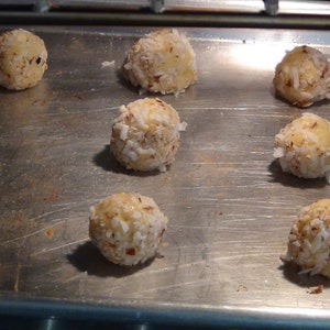 Puede incluir: Una bandeja para hornear con nueve macarons redondos de coco blanco. Los macarons est&aacute;n dispuestos en un c&iacute;rculo en la bandeja para hornear.
