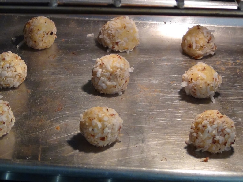 Puede incluir: Una bandeja para hornear con nueve macarons redondos de coco blanco. Los macarons est&aacute;n dispuestos en un c&iacute;rculo en la bandeja para hornear.