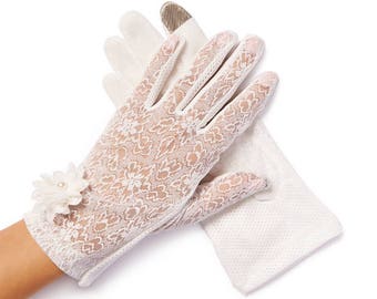 Puede incluir: Un par de guantes de encaje blanco con un pequeño adorno de flor blanca en la muñeca.