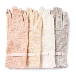 May include: Four pairs of delicate lace gloves in different shades of beige, cream, and gray. Each glove has a small white bow at the wrist.