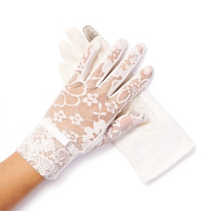 May include: A pair of white lace gloves with a floral pattern. The gloves are shown on a hand with the wrist portion of the glove folded back.