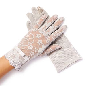 May include: A pair of gray lace gloves with a floral pattern. The gloves have a bow on the wrist and are made of a sheer fabric.