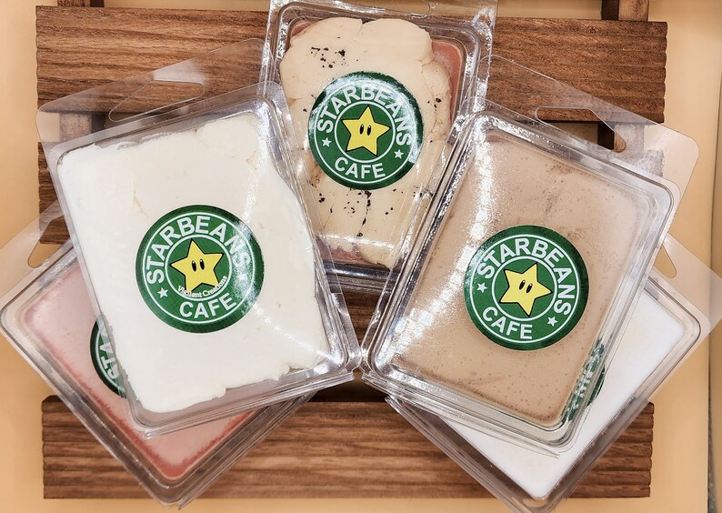 May include: Four clear plastic containers with lids, each containing a different coloured wax melt. The wax melts are labelled "Starbeans Cafe" with a green star logo.
