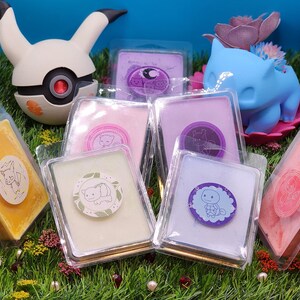 May include: Assortment of six wax melts in clear plastic containers with various colors and designs. The wax melts feature cute animal illustrations and are arranged on a bed of green grass.