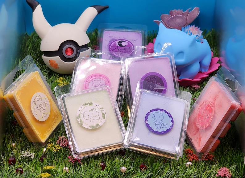 May include: Assortment of six wax melts in clear plastic containers with various colors and designs. The wax melts feature cute animal illustrations and are arranged on a bed of green grass.