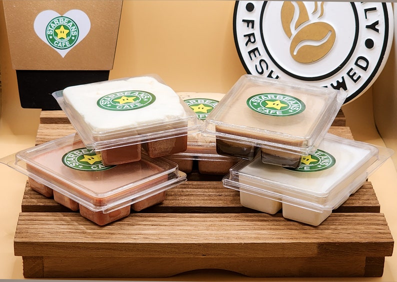 May include: Six wax melts in clear plastic containers with a brown, white and beige wax. Each container has a green and yellow logo that says "Starbeans Cafe" with a star and coffee bean.