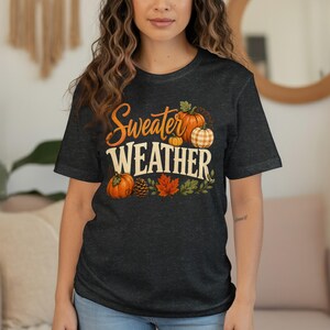 Dark t-shirt with "Sweater Weather" text featuring pumpkins and fall leaves.