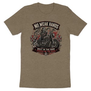 T-shirt graphic of a skeleton riding a motorcycle, text "NO WEAK HANDS BUILT IN THE SHOP FORGED ON THE ROAD".