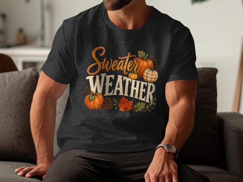 Dark crew neck t-shirt with "Sweater Weather" text and pumpkins, leaves, and pinecone graphic.