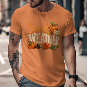 Orange t-shirt with "Sweeter Weather" text and pumpkins, pinecones, and fall leaves graphic.
