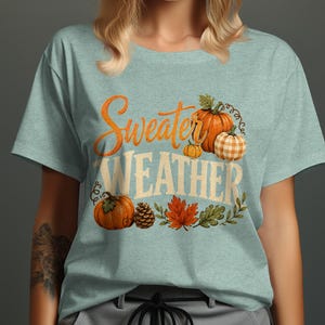 Light blue t-shirt with "Sweater Weather" text and pumpkins, leaves.