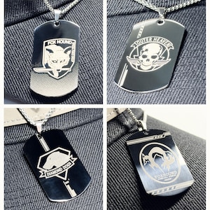 Puede incluir: Cuatro colgantes de chapa de acero inoxidable en cadenas plateadas. Cada chapa presenta un diseño diferente: "FOX HOUND" con un zorro, "OUTER HEAVEN" con una calavera, "DIAMOND DOGS" con un perro y "FOXHOUND SPECIAL FORCE GROUP" con un zorro.