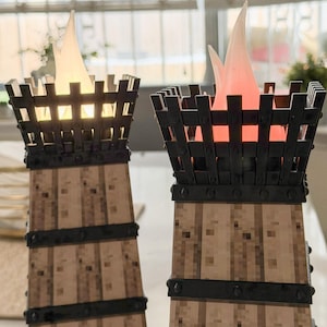 May include: Two decorative torch-shaped lamps with a faux wood base and black metal cage top. The lamps have a flickering flame effect, one with a warm white glow and the other with a red glow, creating a cozy ambiance. The lamps are designed to resemble medieval torches.