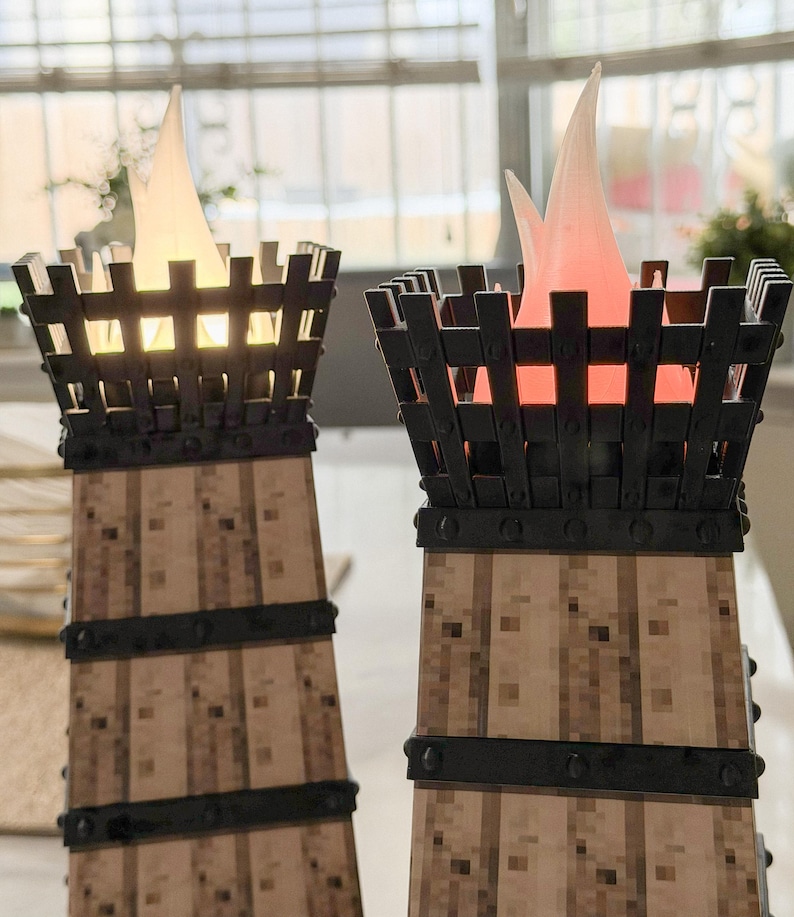 May include: Two decorative torch-shaped lamps with a faux wood base and black metal cage top. The lamps have a flickering flame effect, one with a warm white glow and the other with a red glow, creating a cozy ambiance. The lamps are designed to resemble medieval torches.