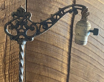 Può includere: Una lampada da terra vintage in metallo nero con un design decorativo a volute e una presa in porcellana bianca.