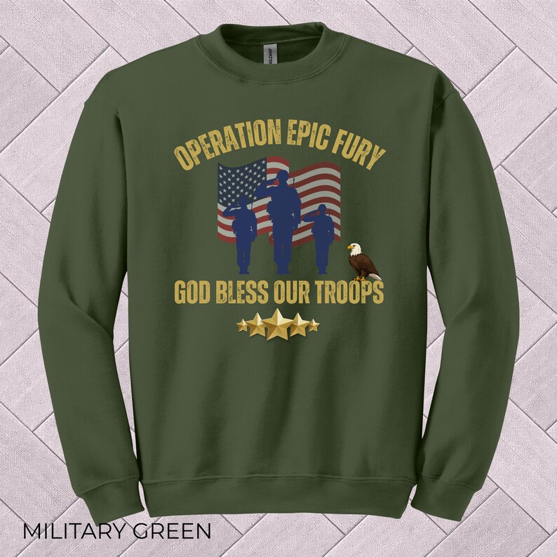 May include: Military green sweatshirt with the text "OPERATION EPIC FURY" and "GOD BLESS OUR TROOPS." The design includes an American flag, silhouettes of soldiers, an eagle, and gold stars. The sweatshirt is a crew neck.