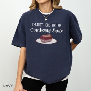 Puede incluir: Camiseta azul marino con el texto "I'M JUST HERE FOR THE Cranberry Sauce" sobre un gr&aacute;fico de una lata de salsa de ar&aacute;ndanos en un plato blanco. La camiseta es de estilo casual.