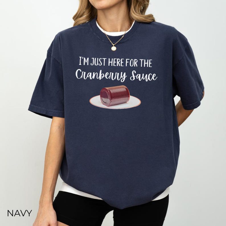 Puede incluir: Camiseta azul marino con el texto "I'M JUST HERE FOR THE Cranberry Sauce" sobre un gr&aacute;fico de una lata de salsa de ar&aacute;ndanos en un plato blanco. La camiseta es de estilo casual.