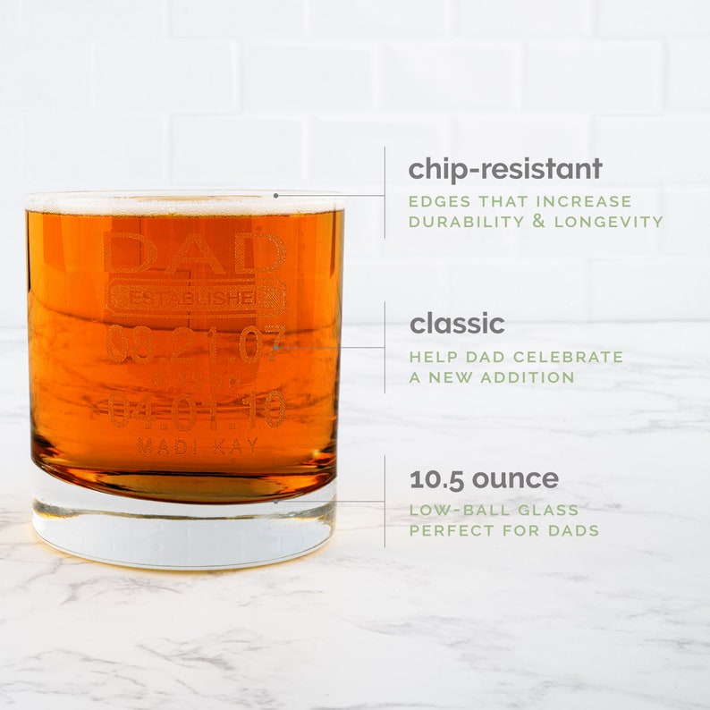 May include: A clear glass with a low-ball shape, filled with a light amber liquid. The glass is engraved with the text "DAD ESTABLISHED 1997" and "MADI KAY". The glass is 10.5 ounces and has chip-resistant edges.